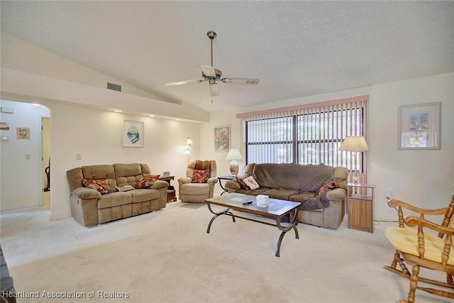 carpeted living room with lofted ceiling, ceiling fan, and a textured ceiling