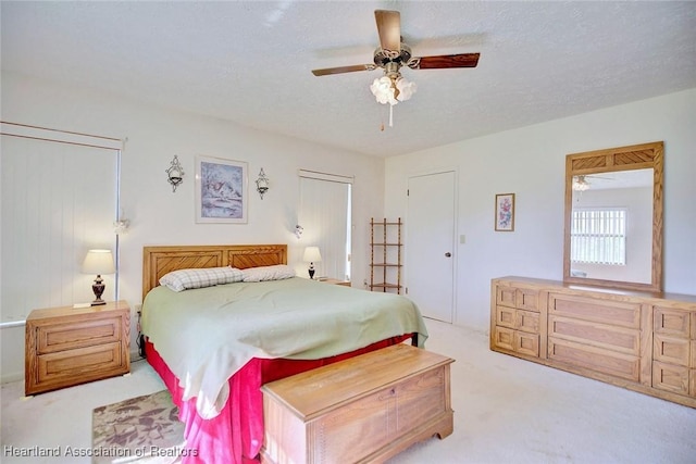 bedroom featuring a textured ceiling, light colored carpet, and ceiling fan