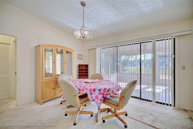 dining space with vaulted ceiling, a textured ceiling, light carpet, and an inviting chandelier