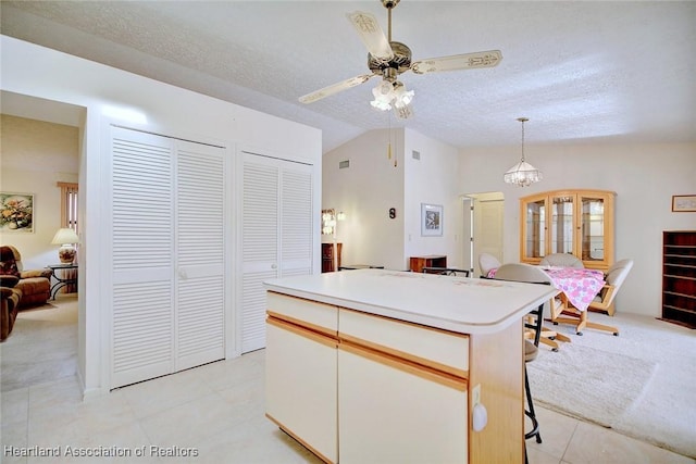 kitchen featuring a textured ceiling, vaulted ceiling, white cabinetry, a kitchen island, and hanging light fixtures