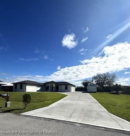 view of front of property with a front yard, an outbuilding, a shed, an attached garage, and concrete driveway