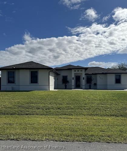 prairie-style house with stucco siding and a front yard