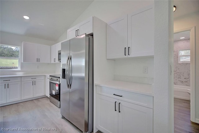 2731 W Albatross Rd, Avon Park, FL 33825 - kitchen with appliances with stainless steel finishes, white cabinetry, light wood-style floors, vaulted ceiling, and recessed lighting