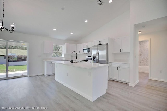 2731 W Albatross Rd, Avon Park, FL 33825 - kitchen featuring stainless steel appliances, light wood finished floors, light countertops, white cabinets, and an island with sink