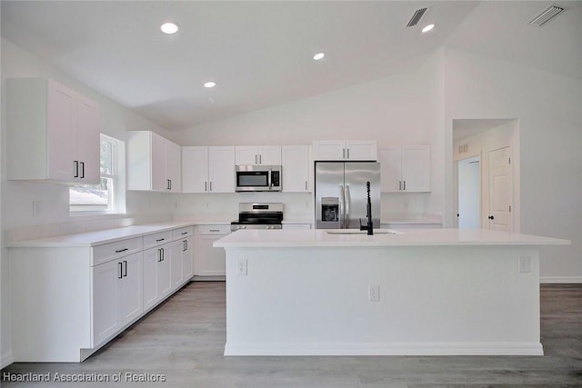 2731 W Albatross Rd, Avon Park, FL 33825 - kitchen with appliances with stainless steel finishes, vaulted ceiling, white cabinetry, a center island with sink, and light countertops