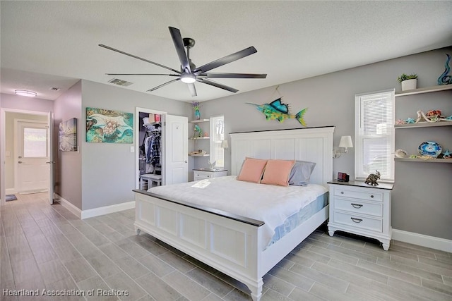 bedroom featuring ceiling fan, a spacious closet, multiple windows, and a closet