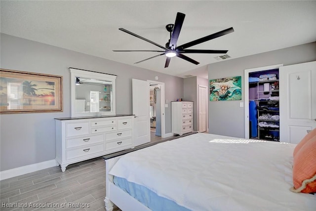 bedroom with a ceiling fan, wood tiled floor, visible vents, and baseboards