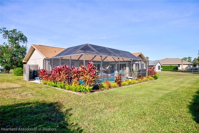 back of property with a yard and glass enclosure