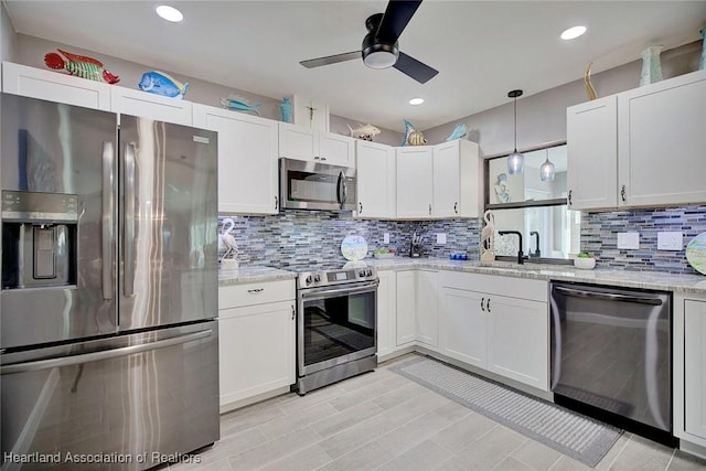 kitchen featuring light stone counters, pendant lighting, stainless steel appliances, decorative backsplash, and white cabinets