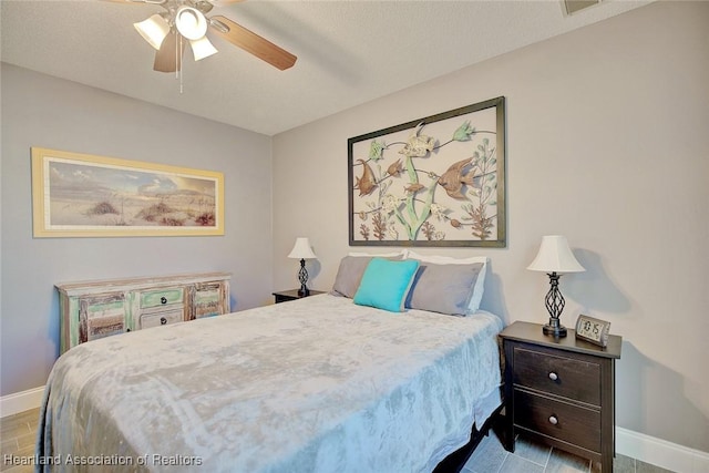 bedroom featuring a textured ceiling, wood finished floors, a ceiling fan, and baseboards