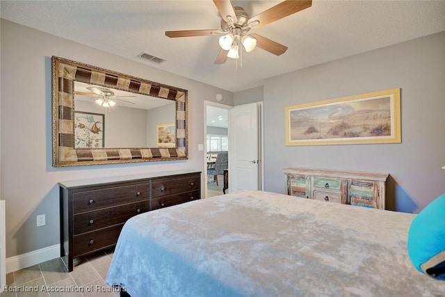 bedroom with baseboards, a textured ceiling, visible vents, and a ceiling fan