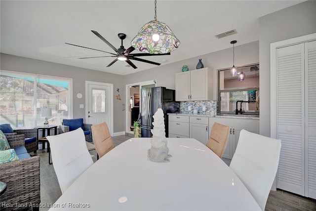 dining area with ceiling fan, dark hardwood / wood-style flooring, and sink