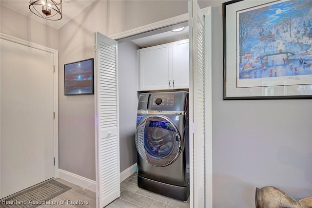 washroom with washer / dryer, cabinet space, and baseboards