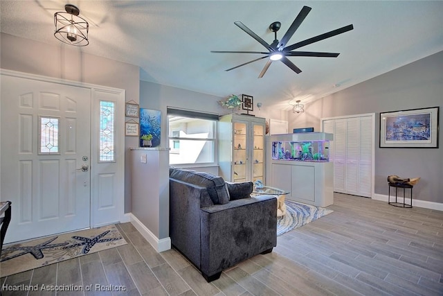 foyer entrance featuring wood finish floors, ceiling fan, lofted ceiling, and baseboards