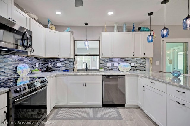 kitchen featuring white cabinetry, sink, light stone counters, decorative light fixtures, and appliances with stainless steel finishes