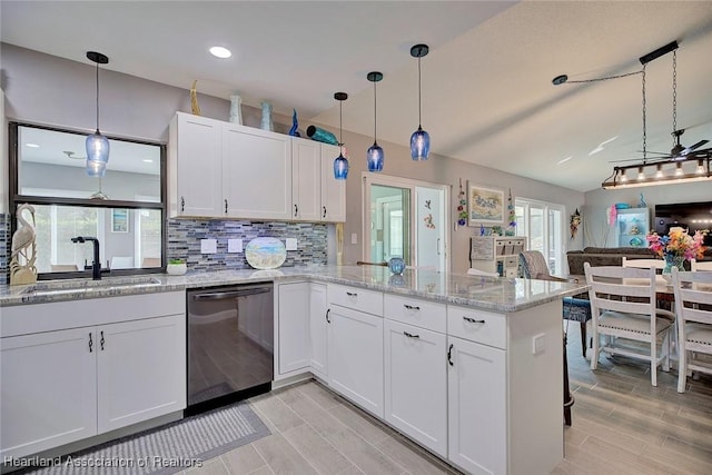 kitchen with tasteful backsplash, stainless steel dishwasher, white cabinets, a sink, and a peninsula