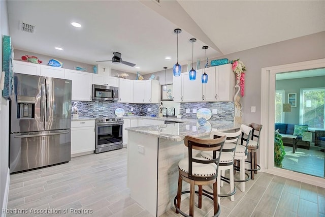 kitchen with stainless steel appliances, a peninsula, white cabinetry, visible vents, and decorative backsplash