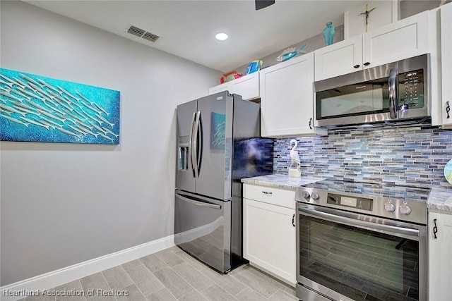 kitchen featuring tasteful backsplash, white cabinetry, light stone countertops, and stainless steel appliances