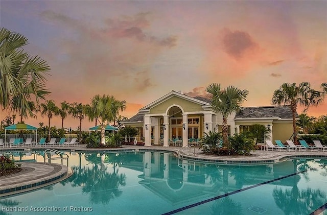 pool at dusk with a patio area