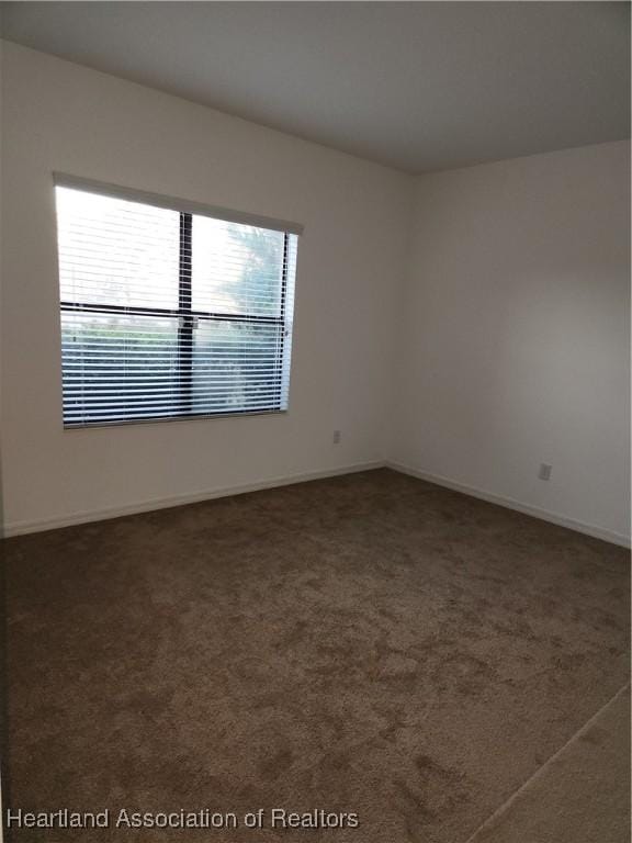 spare room featuring dark colored carpet