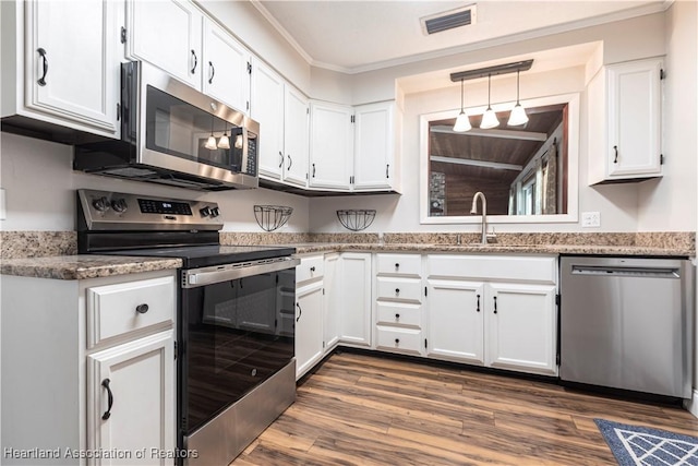 1090 Knollwood Cir, Wauchula, FL 33873 - kitchen with appliances with stainless steel finishes, white cabinetry, dark wood finished floors, crown molding, and light stone counters