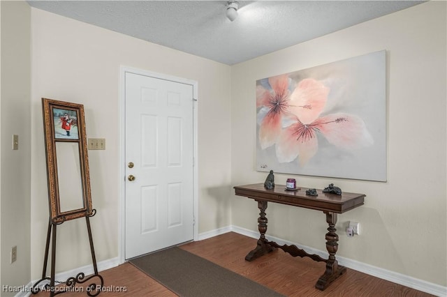 entrance foyer featuring dark wood-style floors, a textured ceiling, and baseboards