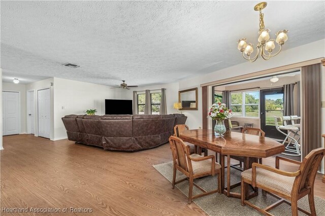 dining room with light wood-style flooring, a textured ceiling, visible vents, and a wealth of natural light