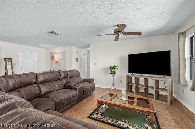 living room featuring visible vents, a textured ceiling, baseboards, and wood finished floors