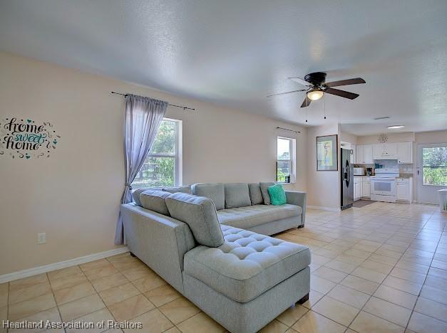 224 Montego Dr, Sebring, FL 33870 - living room featuring light tile patterned floors, baseboards, and a ceiling fan