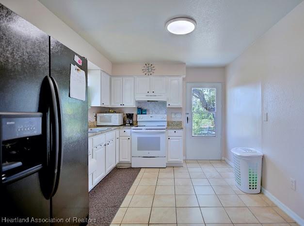 224 Montego Dr, Sebring, FL 33870 - kitchen with light countertops, white cabinetry, white appliances, and under cabinet range hood