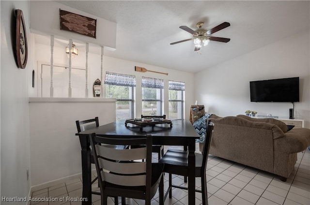 dining space featuring baseboards, a ceiling fan, light tile patterned flooring, and vaulted ceiling