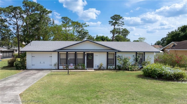 single story home with a garage, driveway, a front lawn, and brick siding
