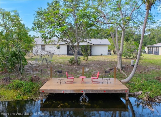 view of dock with a lawn and a water view