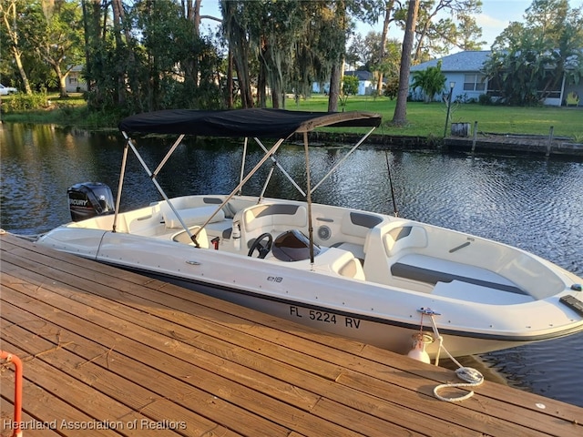 view of dock with a yard and a water view