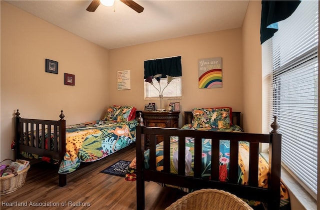 bedroom featuring ceiling fan, multiple windows, and wood finished floors