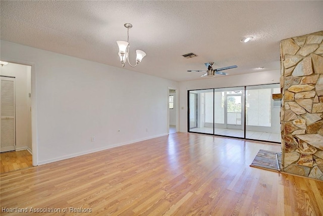 unfurnished room with ceiling fan with notable chandelier, light hardwood / wood-style floors, and a textured ceiling