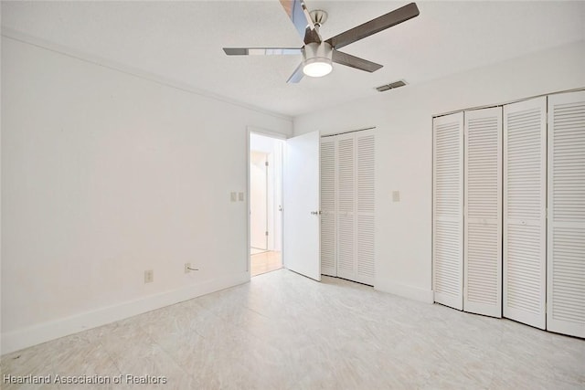 unfurnished bedroom featuring ceiling fan and multiple closets