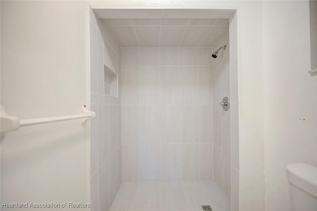 bathroom with tiled shower and toilet