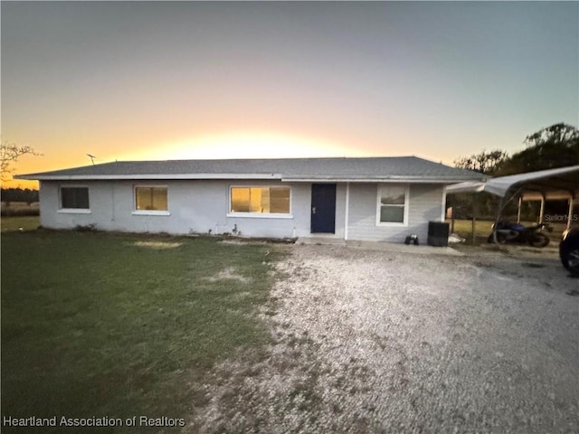 single story home featuring a carport and a yard