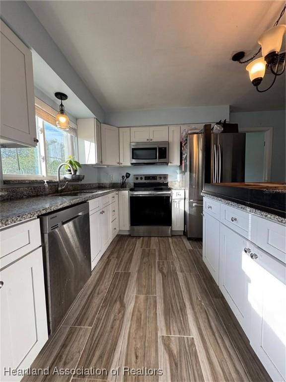 kitchen with dark stone countertops, sink, stainless steel appliances, and white cabinets