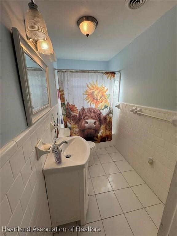 bathroom featuring tile walls, vanity, tile patterned floors, and toilet