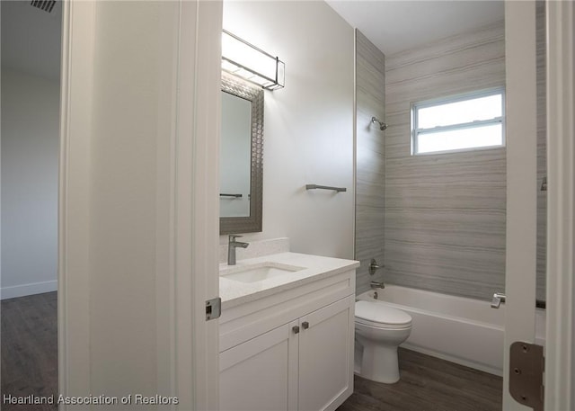 full bathroom featuring hardwood / wood-style floors, tiled shower / bath combo, toilet, and vanity