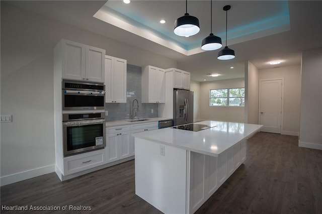 kitchen featuring a raised ceiling, sink, black appliances, decorative light fixtures, and white cabinets