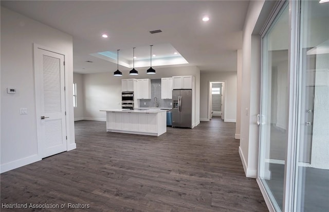 kitchen with stainless steel fridge, a tray ceiling, decorative light fixtures, white cabinetry, and a kitchen island