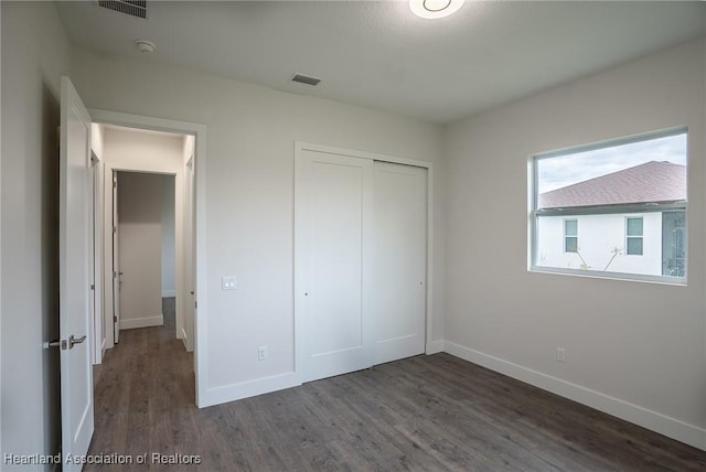 unfurnished bedroom featuring dark hardwood / wood-style flooring and a closet