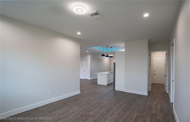 interior space with a raised ceiling, dark wood-type flooring, and a textured ceiling