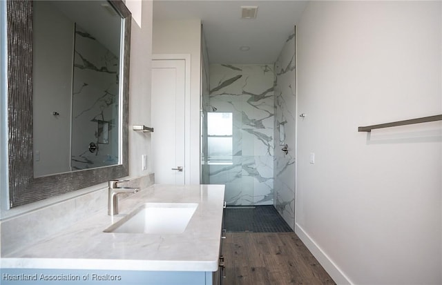 bathroom with a tile shower, hardwood / wood-style floors, and vanity