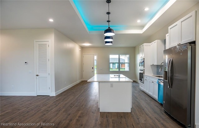 kitchen featuring stainless steel appliances, a kitchen island, dark wood-type flooring, white cabinetry, and hanging light fixtures