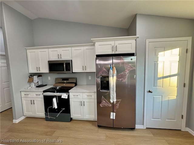 kitchen featuring light hardwood / wood-style floors, white cabinetry, lofted ceiling, and stainless steel appliances