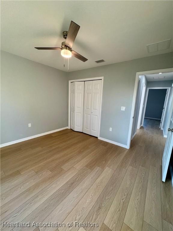 unfurnished bedroom featuring ceiling fan, a closet, and light hardwood / wood-style flooring